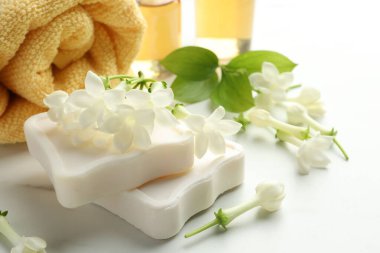 Sabun kalıpları, yasemin çiçekleri ve beyaz mermer masada havlu, yakın plan.