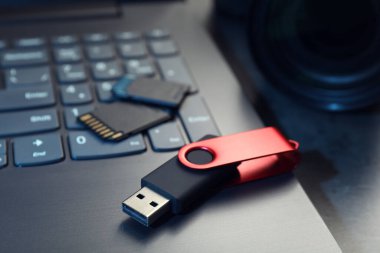SD hafıza kartları, USB flaş bellek ve laptop koyu gri tabloda, yakın plan