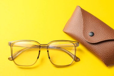 Sarı arka planda şık gözlükleri olan bir çanta.