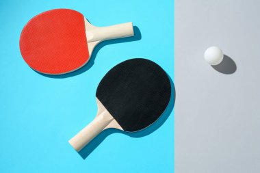 Renkli arka planda pinpon raketleri ve top, üst görünüm