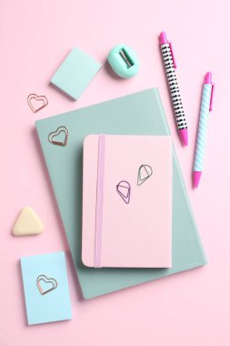 Pembe arka planda kalemler ve diğer kırtasiyeler, düz konum