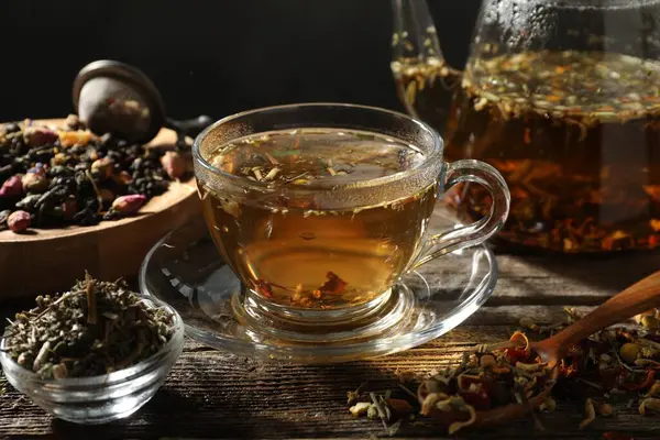 Bitki çayı ve kuru yaprakları ahşap masaya serpmek, yakın plan.