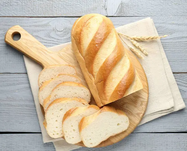 Gri ahşap masada bir somun ekmek ve dikenler kes.