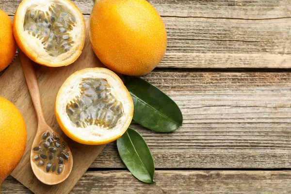 Olgun tutku meyveleri, tohumlar ve yapraklar ahşap masada, düz yerde. Metin için boşluk