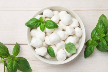 Lezzetli mozzarella peyniri topları kasede ve fesleğen açık ahşap masada, düz yerde