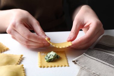 Beyaz masada peynirli ve ıspanaklı ravioli yapan kadın, yakın plan.