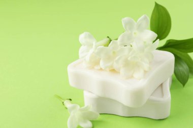 Açık yeşil arka planda sabun ve yasemin çiçekleri, yakın plan. Metin için boşluk