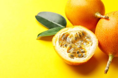 Sarı arka planda olgun çarkıfelek meyveleri ve yaprakları, yakın plan. Metin için boşluk