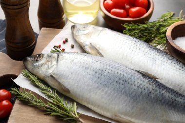 Tuzlu ringa balıkları, baharatlar ve domatesler masada, yakın plan.