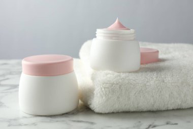 Beyaz mermer masanın üzerinde bir kavanoz nemlendirici vücut kremi, yakın plan.