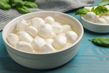 Mozzarella peynir topları ve fesleğen mavi ahşap masada, yakın plan.