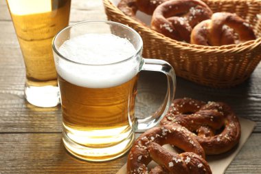 Lezzetli krakerler ve bira kupaları ahşap masada, yakın plan.