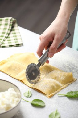 Işık masasında ravioli kesen kadın, yakın plan.