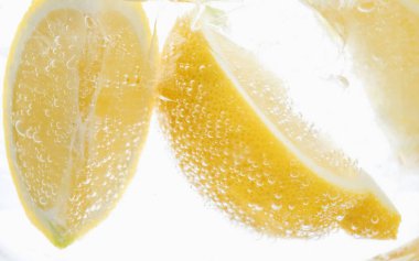 Beyaz arka planda limon dilimleri ile soda tazeleniyor, yakın plan.