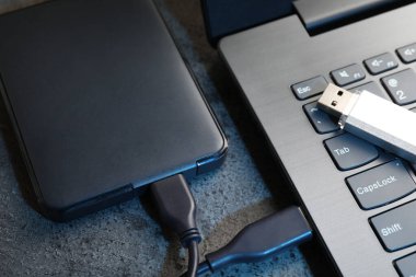 USB flash disk, kablo ve dizüstü bilgisayarlı sabit disk koyu gri masa, yakın plan
