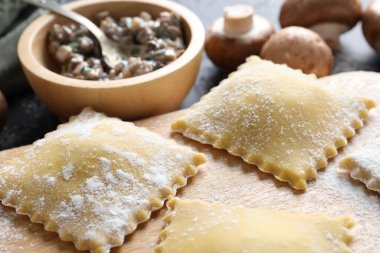 Pişmemiş ravioli ve mantarlar siyah masada, yakın plan.
