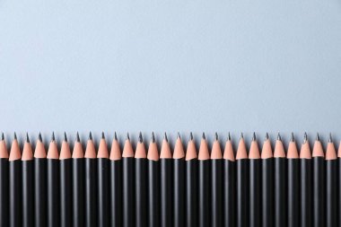Açık gri arka planda, düz zeminde bir sürü keskin grafit kalem var. Metin için boşluk
