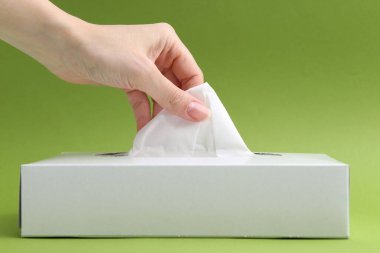 Yeşil arka planda mendili kutusundan çıkaran kadın, yakın plan.