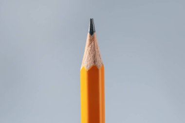 Gri arkaplanda keskin bir grafit kalem, yakın plan.