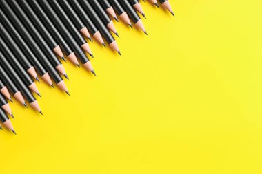 Sarı arka planda bir sürü keskin grafit kalem, düz bir zemin. Metin için boşluk