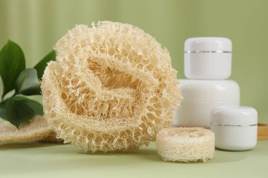 Zeytin arka planında banyo süngeri ve kozmetik ürünlerin kavanozları, yakın plan