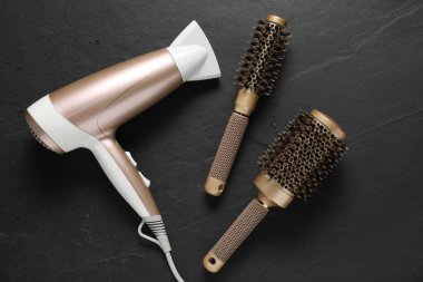 Yuvarlak fırçalar ve kurutma makinesi siyah masada, düz yerde.