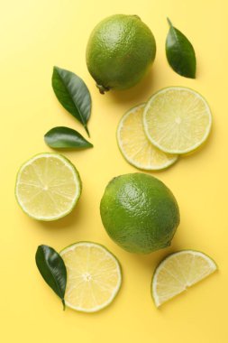 Taze limon ve yeşil yapraklar sarı arka planda, düz yatıyordu.