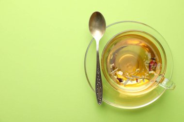 Cam fincanda nefis bitki çayı ve açık yeşil arka planda kaşık, üst manzara. Metin için boşluk