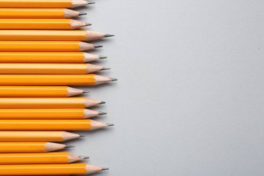 Gri arka planda keskin grafit kalemler, düz. Metin için boşluk