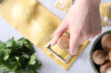 Işık masasında ravioli kesen kadın, üst manzara.