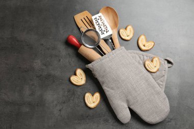Fırın eldivenindeki farklı mutfak aletleri ve gri masadaki kurabiyeler, düz yatak. Metin için boşluk