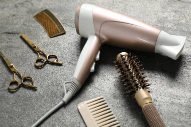 Gri dokulu arka planda farklı saç şekillendirme araçları, yakın plan