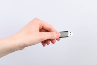 Açık gri arka planda modern flash diski olan adam, yakın plan.