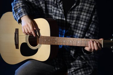 Siyah arka planda gitar çalan kadın, yakın plan