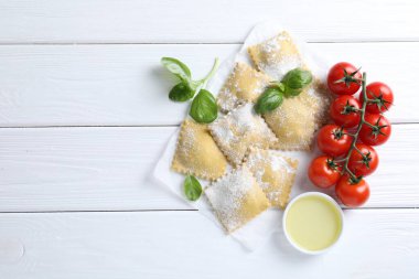 Pişmemiş ravioli, fesleğen, domates ve yağlı beyaz ahşap masa, düz yatak. Metin için boşluk