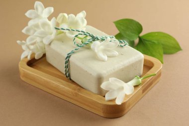 Açık kahverengi arka planda sabun ve yasemin çiçekleri, yakın plan.