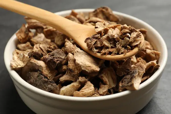 Kuru hindiba kökleri kasede ve kaşıklar karanlık masada, yakın plan.