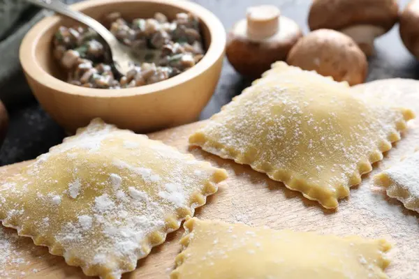 Pişmemiş ravioli ve mantarlar siyah masada, yakın plan.