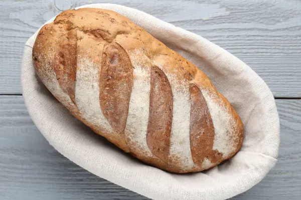 Gri ahşap masada, sepetin içinde bir somun ekmek.