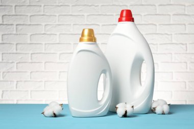 Beyaz tuğla duvara karşı açık mavi masada yumuşatıcı ve pamuk çiçekleri.