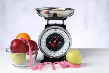 Beyaz ahşap masa üzerinde yulaf, meyve ve mezura ile mutfak pulları