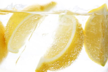 Beyaz arka planda limon dilimleri ile soda tazeleniyor, yakın plan.