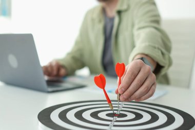 Dart oklu bir adam içeride çalışırken dart tahtasına nişan alıyor, yakın plan.