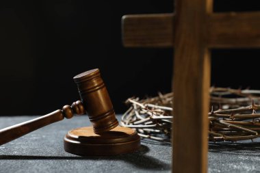 Dikenli taç, yargıç tokmağı ve ahşap haç, koyu dokulu arka plan, yakın plan.