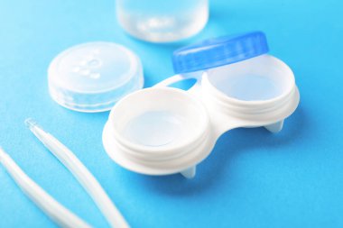 Açık mavi arkaplanda kontak lensler ve cımbızlar, yakın plan