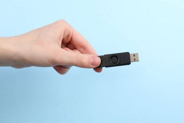 Flaş belleği açık mavi arkaplanda tutan kadın, yakın plan.