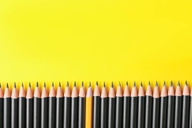 Sarı arka planda bir sürü keskin grafit kalem, düz bir zemin. Metin için boşluk