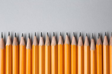 Gri arka planda keskin grafit kalemler, düz. Metin için boşluk