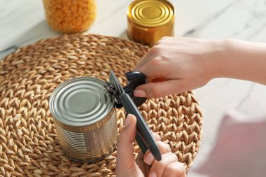 Beyaz mermer masada konserve açacağıyla konserve açan kadın, yakın plan.