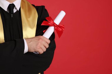 Mezuniyetten sonra kırmızı arka planda diplomalı öğrenci, yakın plan. Metin için boşluk